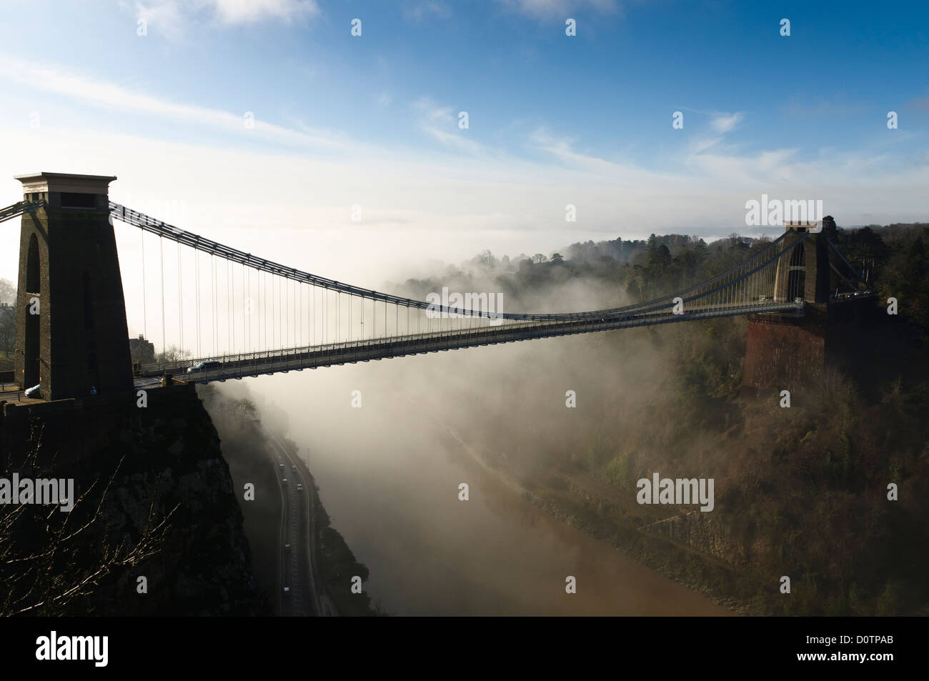 Bristol`s famous Clifton suspension bridge with low mist or cloud sitting in the Avon gorge backlit by morning sunshine. Stock Photo
